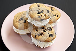 Homemade Chocolate Chip Cookie Ice Cream Sandwich on a pink plate on a black surface, low angle view. Close-up