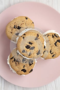 Homemade Chocolate Chip Cookie Ice Cream Sandwich on a pink plate on a white wooden background, top view. Overhead, from above,