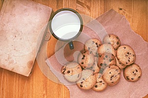 Homemade chocolate chip cookies, milk cup and vintage book