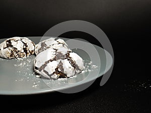 Homemade chocolate cookies. Chocolate brownie cookies in powdered sugar in black background. Selective focus