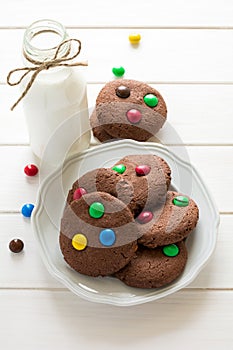 Homemade chocolate cookies decorated with colored candy drops and bottle of milk