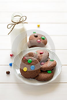 Homemade chocolate cookies decorated with colored candy drops and bottle of milk