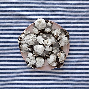 Homemade Chocolate Crinkle Cookies on a pink plate, overhead view. Flat lay, overhead, from above