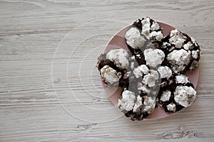 Homemade Chocolate Crinkle Cookies on a pink plate, top view. Copy space