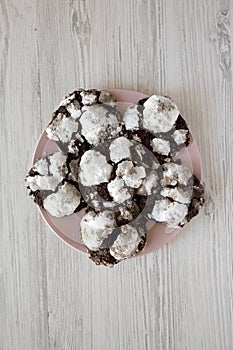 Homemade Chocolate Crinkle Cookies on a pink plate on a white wooden background, top view. Flat lay, overhead, from above