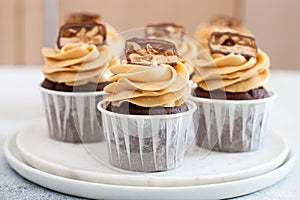 Homemade chocolate dough cupcakes with peanut butter frosting and snickers bites. Selective focus