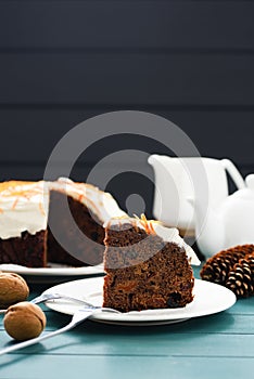 Homemade chocolate fruit cake with cream cheese icing and orange peel on blue background copyspace