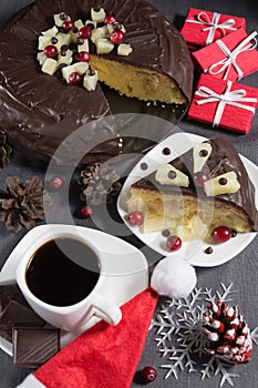 Homemade chocolate-glazed pineapple cake and a cup of coffee with three pieces of chocolate with christmas decorations