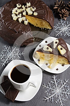 Homemade chocolate-glazed pineapple cake and a cup of coffee with three pieces of chocolate with christmas decorations