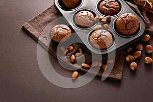 Homemade chocolate muffins brownies with cinnamon, almonds and hazelnuts on brown paper background