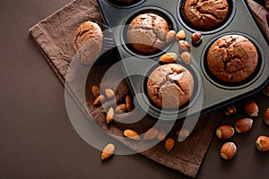 Homemade chocolate muffins brownies with cinnamon, almonds and hazelnuts on brown paper background