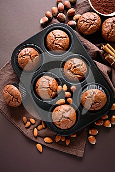 Homemade chocolate muffins brownies with cinnamon, almonds and hazelnuts on brown paper background