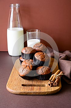 Homemade chocolate muffins brownies with cinnamon and milk on brown paper background