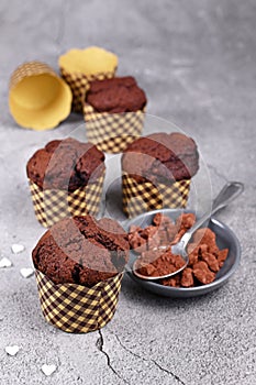 Homemade chocolate muffins in paper case with cup and spoon with cocoa powder and star shaped sugar sprinkles