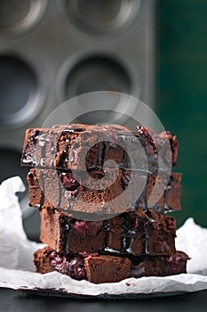 Homemade chocolate sweet brownies cakes with cherry and chocolate sauce or syrup on a dark background