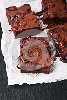 Homemade chocolate sweet brownies cakes with cherry and chocolate sauce or syrup on a dark background, horizontal