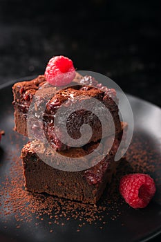 Homemade chocolate sweet brownies cakes with cherry and raspberries on a dark background