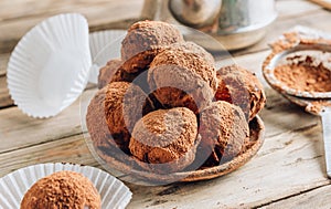 Homemade chocolate truffles candy ball on a plate sprinkled with cocoa on a rustc wooden background. photo