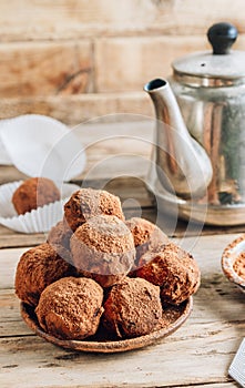 Homemade chocolate truffles candy ball on a plate sprinkled with cocoa on a rustc wooden background. photo