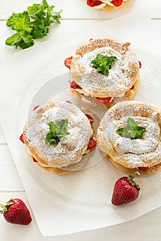 Homemade choux pastry rings with cottage cheese cream and strawberries decorated mint leaves