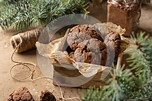 Homemade christmas chocolate cookies in wooden box on brown festive background with fir tree branches. Christmas holiday