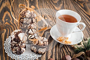 Homemade Christmas cookies gingerbread with cracks, chocolate pastries, a cup of tea, baby hands take a gift on a dark vintage woo