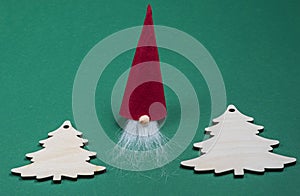 Homemade Christmas craft decorations.Red dwarf and wooden Christmas tree on green background