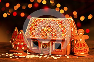 Homemade christmas gingerbread house on a table. Christmas tree lights on the background