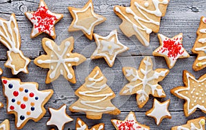 Homemade Christmas star, spruce and snowflake cookies with white frosting on wooden grey background, top view