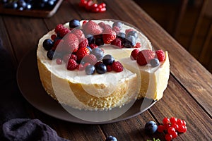 Homemade Christmas winter berry fruit cheesecake on wooden dark table. Creamy mascarpone dessert.