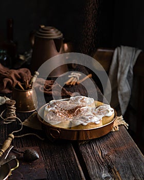 Homemade cinnamon roll buns in vintage copper round pan on wooden rustic table