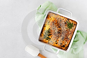 Homemade closed pie with vegetables on a white concrete background.