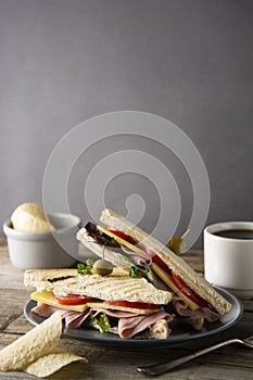 Homemade club sandwich. Toasted white bread triangles with ham, cheese fresh vegetables. Wooden table