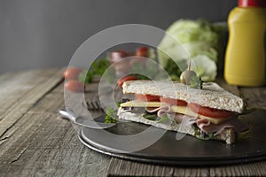 Homemade club sandwich. Toasted white bread triangles with ham, cheese fresh vegetables. Wooden table