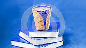 Homemade coffee latte with cinnamon and three books on blue background. Shades of blue, copy space, 16:9 panoramic