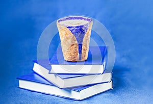 Homemade coffee latte with cinnamon and three books on blue background. Shades of blue, copy space