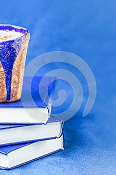 Homemade coffee latte with cinnamon and three books on blue background. Shades of blue, copy space