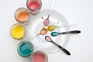 Homemade colorful paints for a baby. Glass jars with dough and food colorants and spoons on a white background. photo