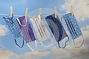 Homemade community face masks from cloth as protection against coronavirus pandemic are hanging on a clothesline, blue sky with