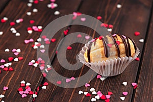 Homemade cookie shaped nuts with cream, chocolate icing on wooden table as a background, red, rose and white sugar sprinkle hearts