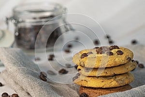 Homemade cookies with chocolate, nuts and coffee beans on a light wooden background with a linen napkin with a background blur.