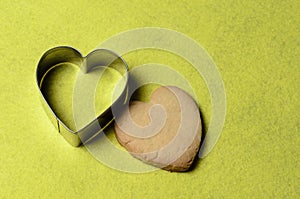 Homemade cookies with a metal baking dish in the shape of a heart on a yellow background