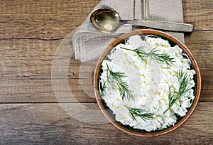 Homemade cottage cheese in a bowl on wooden table.