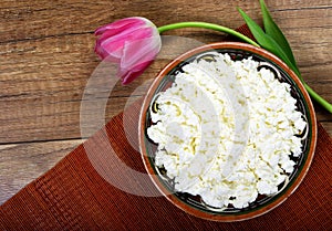 Homemade cottage cheese in a bowl on wooden table.