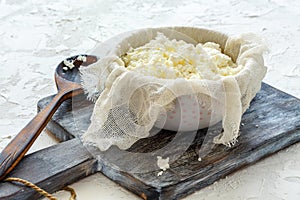 Fresh cottage cheese in a bowl and cheesecloth. photo