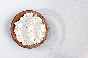 Homemade cottage cheese, curd in a wooden bowl on a grey rustic background. Healthy food.