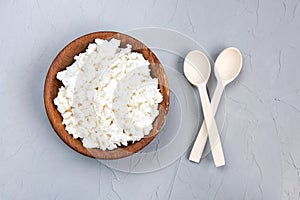 Homemade cottage cheese, curd in a wooden bowl on a grey rustic background. Healthy food.