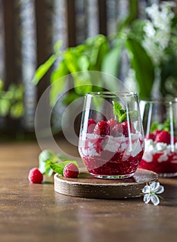 Homemade cottage cheese with fresh raspberries in a glass glass on a rustic wooden background