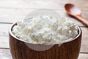 Homemade cottage cheese in a wooden bowl on old wooden table