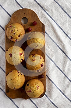 Homemade Cranberry Muffins with Orange Zest on a rustic wooden board on cloth, top view. Flat lay, overhead, from above. Space for